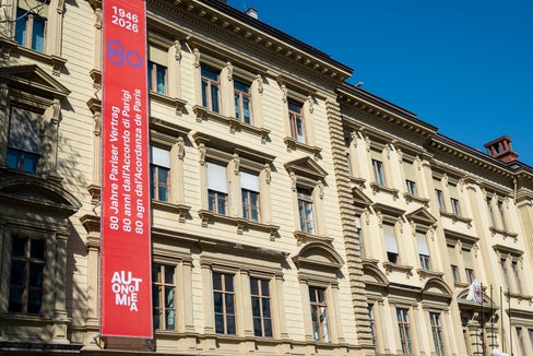 Un banner ben visibile sulla facciata di Palazzo Widmann a Bolzano annuncia il significativo anniversario 2026, che celebra gli 80 anni del Trattato di Parigi. (Foto: USP/Fabio Brucculeri)