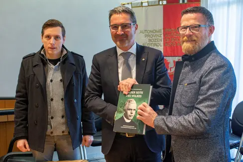 Il comandante provinciale della Schützen Seppi (nella foto a destra) e il consigliere del direttivo Zemmer (a sinistra) consegnano al presidente Kompatscher il libro dedicato alla vita del clero altoatesino durante il fascismo. (Foto:ASP/Fabio Brucculeri)