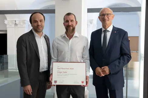 Gregor Sailer (Mitte) hat am 14. September aus den Händen von Kulturlandesrat Philipp Achammer (links) und dem Tiroler Landeshauptmann und Kulturreferenten Anton Mattle (rechts) den Paul-Flora-Preis 2026 erhalten. (Foto: Land Tirol/Sidon)