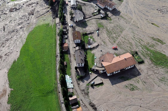 Archivbild: Der Blick auf den Großbergbach und den Weiler Fußendraß am Tag nach der Überschwemmung, am 5. August 2012, zeigt das Ausmaß der Schäden. Im Hintergrund hinter der Baumgruppe erkennbar die Rückhaltesperre, die erst knapp ein Jahr vor dem Unwetterereignis errichtet worden war. (Foto: LPA/Landeswarnzentrum in der Agentur für Bevölkerungsschutz)