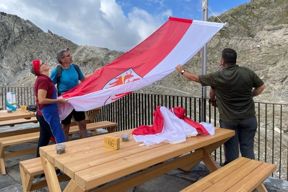 Il presidente Kompatscher mentre issa la bandiera della Provincia insieme ai gestori del rifugio Petrarca (Foto: ASP/G.News)