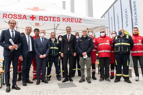 Davanti al centro di accoglienza (da sinistra): il direttore della protezione civile Unterweger, l'assessore Schuler, il commissario del governo Cusumano, il presidente della Provincia Kompatscher, il capo della protezione civile Curcio con i rappresentanti della Croce Bianca e della Croce Rossa (Foto: ASP/Ivo Corrà)