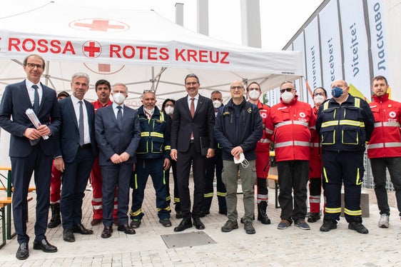 Davanti al centro di accoglienza (da sinistra): il direttore della protezione civile Unterweger, l'assessore Schuler, il commissario del governo Cusumano, il presidente della Provincia Kompatscher, il capo della protezione civile Curcio con i rappresentanti della Croce Bianca e della Croce Rossa (Foto: ASP/Ivo Corrà)