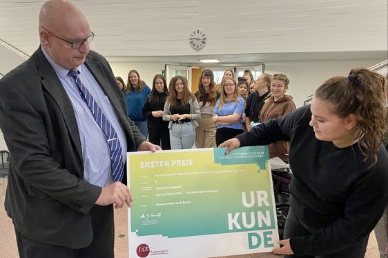 Wettbewerbsleiter Hans-Georg Lambertz bei der heutigen Prämierungsfeier in Tisens mit Eva Oberperfler und den Schülerinnen der Siegerklasse im Hintergrund (Foto: LPA/Fachschule Tisens)