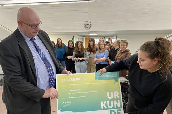 Wettbewerbsleiter Hans-Georg Lambertz bei der heutigen Prämierungsfeier in Tisens mit Eva Oberperfler und den Schülerinnen der Siegerklasse im Hintergrund (Foto: LPA/Fachschule Tisens)