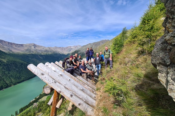 Foto di gruppo sulle strutture in legno di protezione dalle valanghe: gli operatori dell'Ufficio sistemazione bacini montani Ovest con i colleghi dell'Ispettorato forestale di Merano durante una visita al sistema di protezione delle valanghe Hochegg a Vernago in Val Senales (Foto: ASP/Ispettorato forestale di Merano)