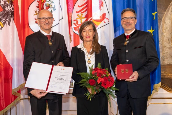 Il presidente del Land Tirolo Anton Mattle (a sinistra) e il presidente della Provincia autonoma di Bolzano Arno Kompatscher (a destra) consegnano l'onorificenza alla scrittrice altoatesina Sabine Gruber (Foto: Land Tirol/Die Fotografen)