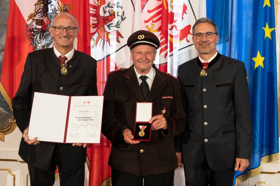 Steht mit seinem langjährigen Einsatz im Feuerwehwesen stellvertretend für verdiente Persönlichkeiten bei den Blaulicht-Organisationen: Anton Schraffl aus St. Georgen bei Bruneck mit den Landeshauptleuten Mattle (l.) und Kompatscher (r.) (Foto: Land Tirol/Die Fotografen)