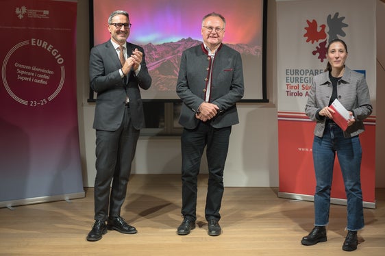 La cungratulazions per Hans Bergmann, tamez, che à fat la fotografia dancà dl calënder, ti ie unides fates dal presidënt dla Euregio y presidënt dla Jonta provinziela de Bulsan Arno Kompatscher, a man ciancia, y dala respunsabla dl pruiet Silvia Ramoser, a man drëta. (Foto: USP/Patrizia Corriero)