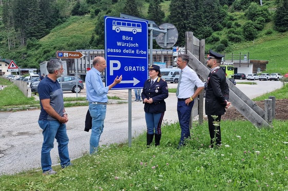Der Direktor des Straßendiensts Götz Rufinatscha, Bürgermeister Giorgio Costabiei, die Leiterin der Straßenpolizei in Südtirol Katia Grenga, Landesrat Daniel Alfreider und Carabinierimajor Innocenzo Colonna besprechen die neue Beschilderung in Pikolein, die Besucher informieren soll, dass das Auto kostenfrei geparkt und der Bus genutzt werden kann, um aufs Würzjoch zu gelangen. (Foto: LPA/Angelika Schrott)