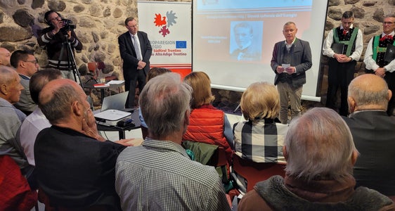 Großer Besucherandrang beim Vortrag des Historikers Michael Gehler (stehend l.) über den deutsch-zimbrischen Politiker Eduard Reut-Nicolussi, zu dem im Rahmen des Euregio-Kulturdonnerstags Eurego-Generalsekretär Christoph von Ach (stehend r.) begrüßte. (Foto: Euregio/Armin Gluderer)