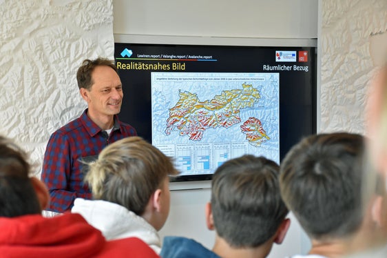 Der Leiter des Lawinenwarndienstes des Landes Tirol, Patrick Nairz, führt Schülerinnen und Schüler der Mittelschule Matrei am Brenner durch die Lawinenausstellung im Eurego-Infopoint. (Foto: Land Tirol)