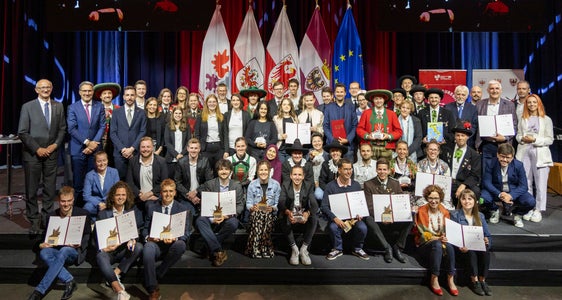 Fotografia de grupa cun duc i premiei y i ghesć d’unëur: undesc persones jëunes y set pruiec à giapà ai 14 de juni dai länder Tirol, Südtirol y Trentin l pest de “Prestazion d’ezelënza – l ulentariat jëunn”. (Foto: Land Tirol/Die Fotografen)