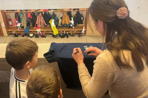Karin Oberkofler firma una maglietta destinata ad uno degli alunni della scuola primaria di Santa Maddalena, uno dei 70 istituti altoatesini coinvolti nel 2025 da questa iniziativa dedicata al valore dello sport e dei Giochi Olimpici. (Foto: USP)
