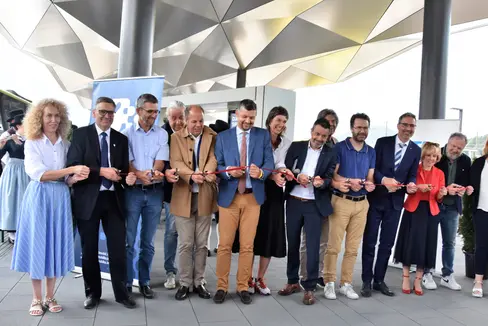 Taglio del nastro all'inaugurazione del Centro di mobilità di Brunico con il presidente Kompatscher (quarto da destra), l'assessore Alfreider (sesto da sinistra), il sindaco di Brunico Griessmair (quinto da destra), il direttore della STA Dejaco (ottavo da sinistra), l'assessora Deeg (terza da sinistra), il presidente della Comunità comprensoriale Steger (secondo da sinistra), le coordinatrici dell'Infopoint Kosaraz (prima da sinistra) e Fink (prima da destra) e i rappresentanti delle imprese edili (Foto: ASP/Angelika Schrott)