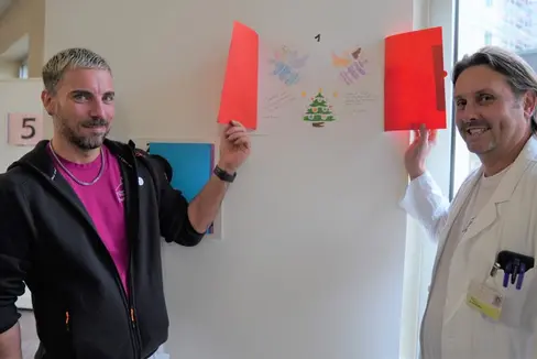Alex Staffler e Davide Gianotti, Primario e Coordinatore tecnico-assistenziale del Reparto di neonatologia e terapia intensiva neonatale alle prese con il calendario d'Avvento donato dai bambini della scuola primaria Galilei di Merano. (Foto: ASP/Direzione istruzione e formazione italiana)
