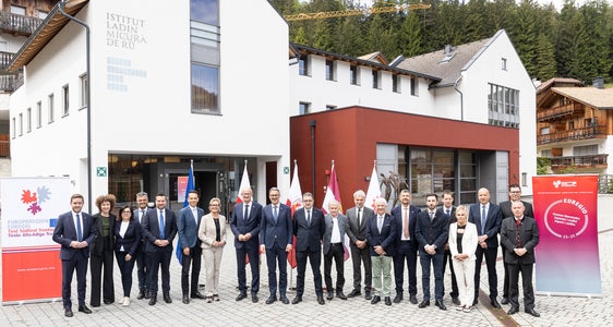 Foto di gruppo dell'Assemblea dell'Euregio con altri ospiti d'onore e dirigenti davanti all'Istitut ladin Micurà de Rü a San Martino in Val Badia: ulteriore rafforzamento delle agevolazioni per le famiglie con l'EuregioFamilyPass. (Foto: USP/Tiberio Sorvillo)