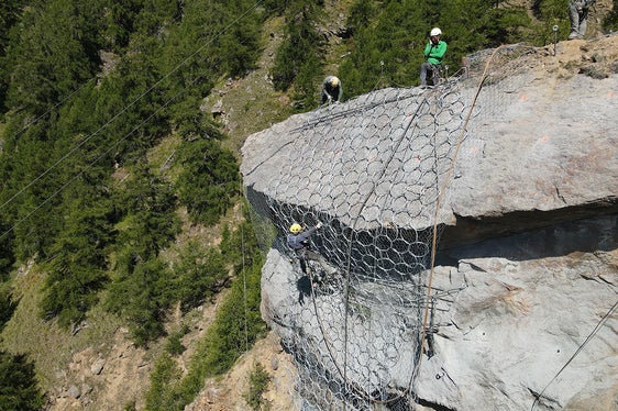 Addetti della ditta Geobau impegnati nella messa in opera delle reti di contenimento in preparazione al brillamento del costone di roccia Kastnknott sopra Colsano. (Foto: ASP/Gnews)