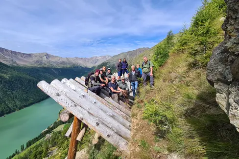 Foto di gruppo sulle strutture in legno di protezione dalle valanghe: gli operatori dell'Ufficio sistemazione bacini montani Ovest con i colleghi dell'Ispettorato forestale di Merano durante una visita al sistema di protezione delle valanghe Hochegg a Vernago in Val Senales (Foto: ASP/Ispettorato forestale di Merano)