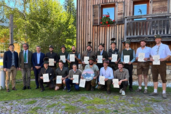 Gruppenbild der Absolventen des 11. Jagdaufseherlehrgangs mit Diplomen und Schützenscheibe und (von links) dem Direktor des Landesamtes für Wildtiermanagement Dominik Trenkwalder, Landesjägermeister Günther Rabensteiner, Forstwirtschaftslandesrat Luis Walcher (Foto: LPA)