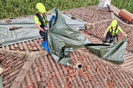 I vigili del fuoco altoatesini in azione sul tetto di un caseggiato colpito dal nubifragio. (Foto: ASP/Vigili del fuoco volontari dell'Alto Adige)