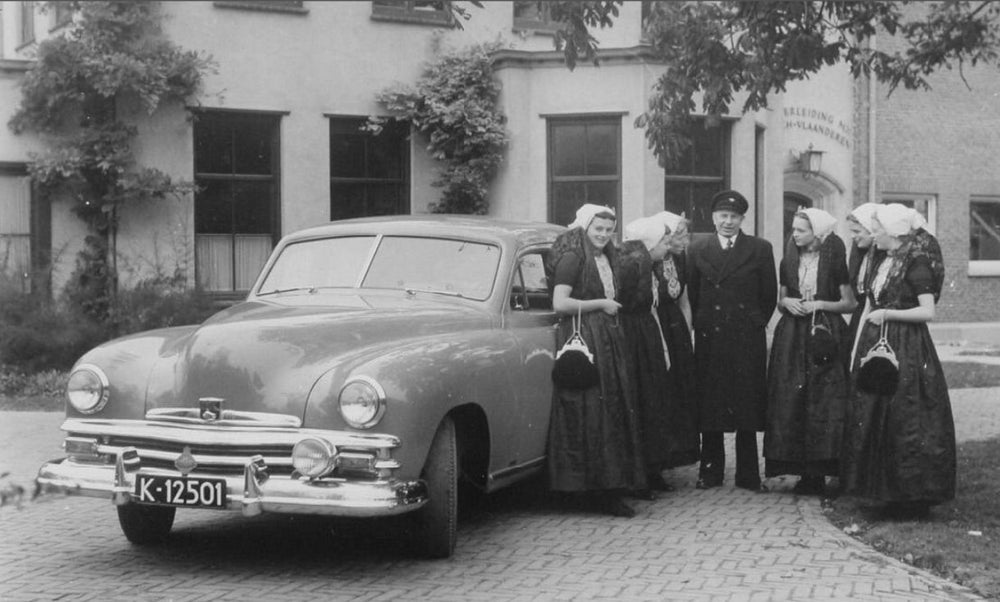 De directeur van de waterleidingmaatschappij in Zeeuws-Vlaanderen, Gerard Dikötter, naast een auto en zes vrouwen.