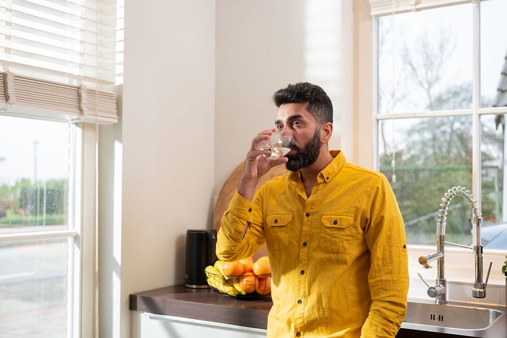 Man drinkt water tegen aanrecht aan