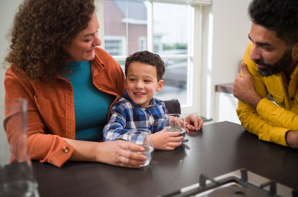 Moeder kind en vader met glas water bij het aanrecht.