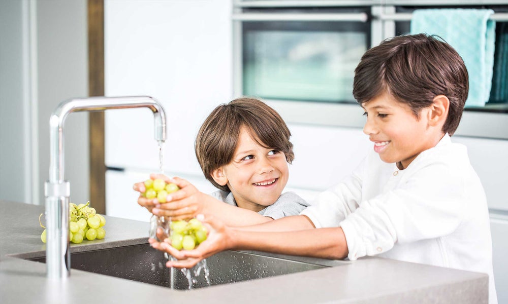 2 kinderen spoelen druiven af onder kraan