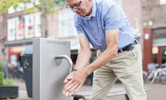 Man wast zijn handen bij een drinkwaterpunt.
