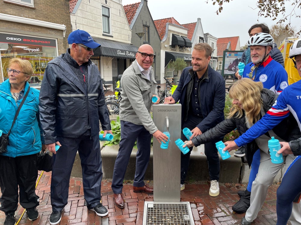 Erik ter Velde en Martijn Hamerslag tappen water in Evides-bidons voor de passerende wielerploeg ‘Tourclub Voorne Putten’.