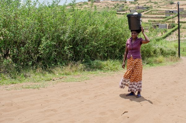 Afrikaanse vrouw draagt een ton met water op haar hoofd
