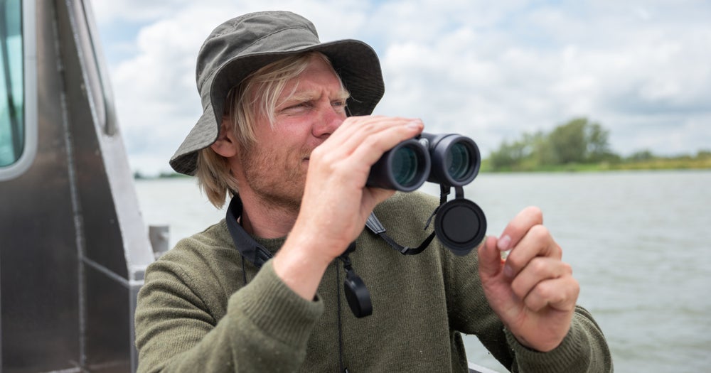 Evides medewerker met verrekijker op zoek naar vogels.