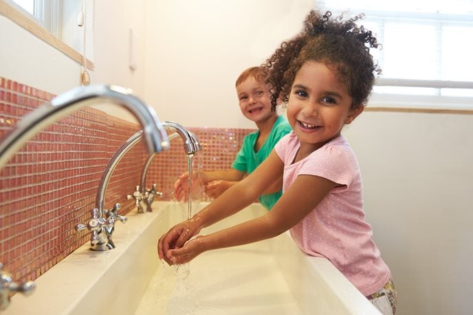 Meisje en een jongetje wassen hun handen onder de kraan op school