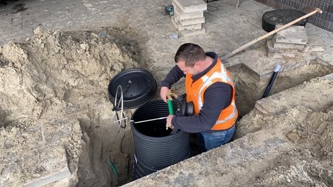 Monteur legt een waterleiding aan in de grond