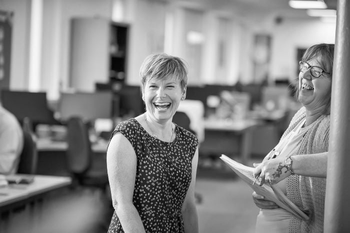 Two colleagues laughing together in an office