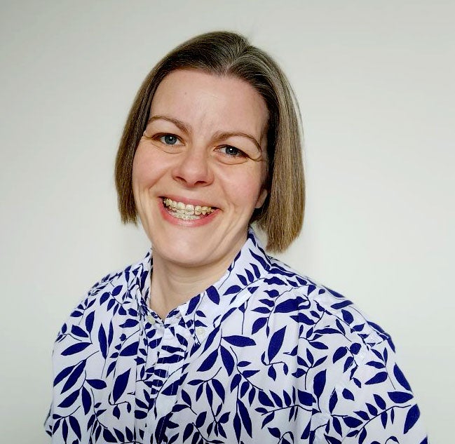 A lady in a blue and white floral shirt smiling at the camera