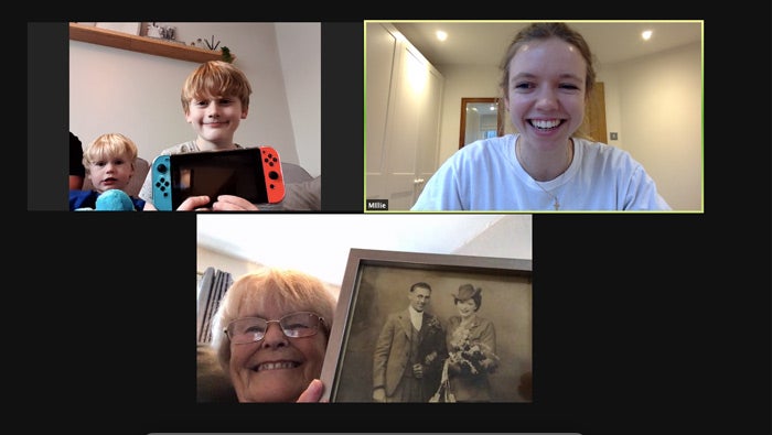 A zoom meeting with two younger people and an older person holding up their posessions