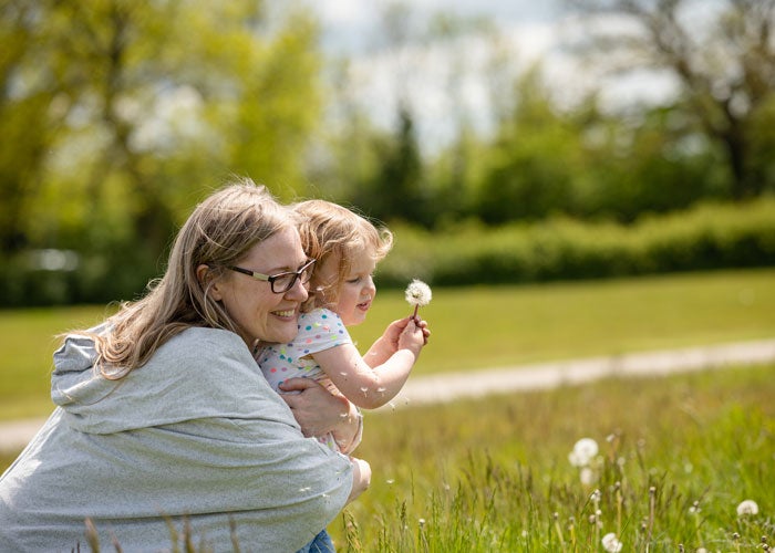Mother hugging daughter in a meadow