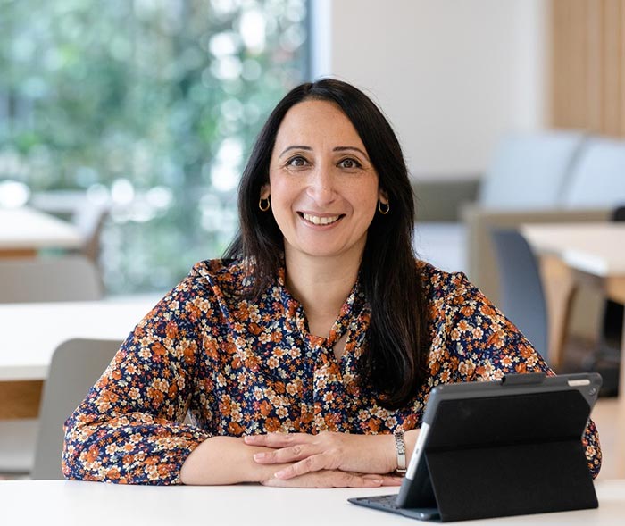 Aasia Nisar, Head of Resident Engagement, sitting at a table, smiling at the camera