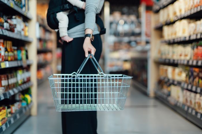 Woman with a baby in a supermarket carrying a shopping basket