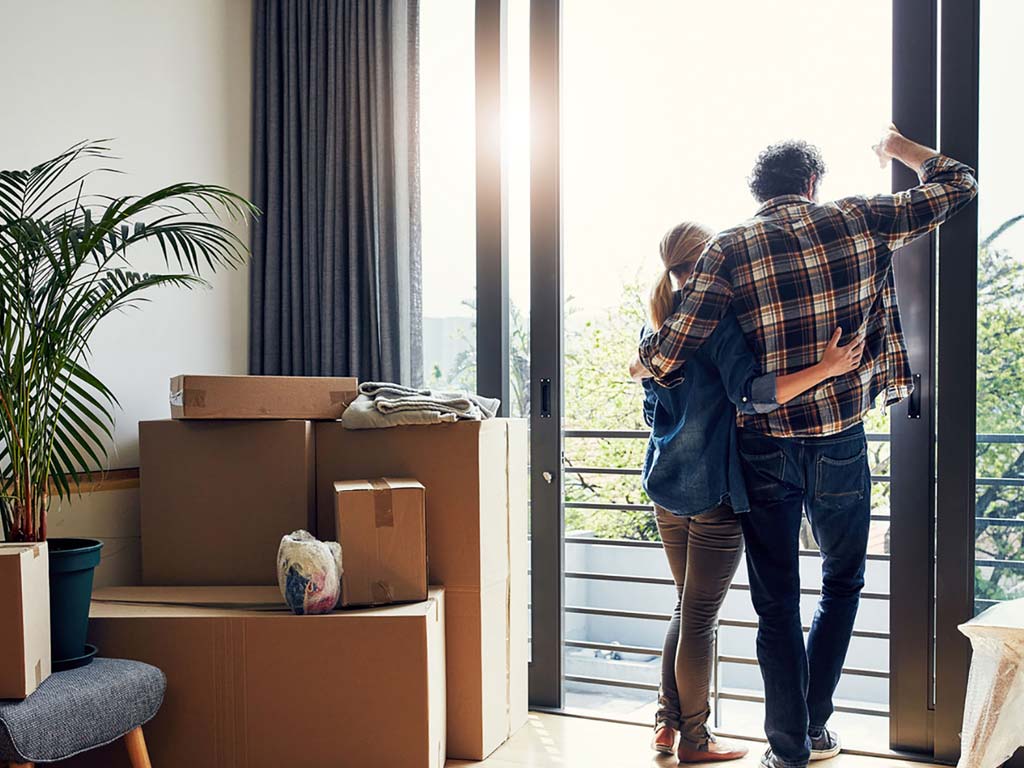 A couple in their new home looking out of their balcony on a sunny day