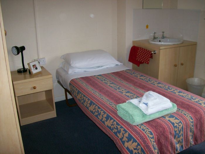 single bed with wash basin and bedside table