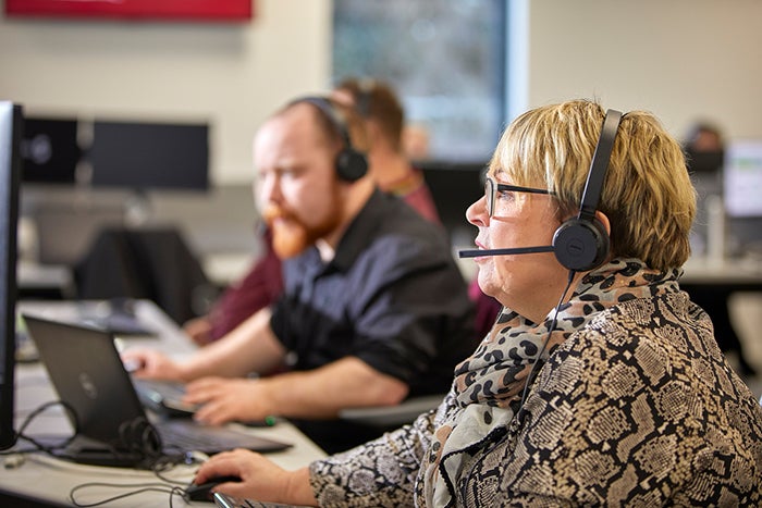 Employees working in the SNG contact centre. They are talking to customers on the phone while wearing headsets