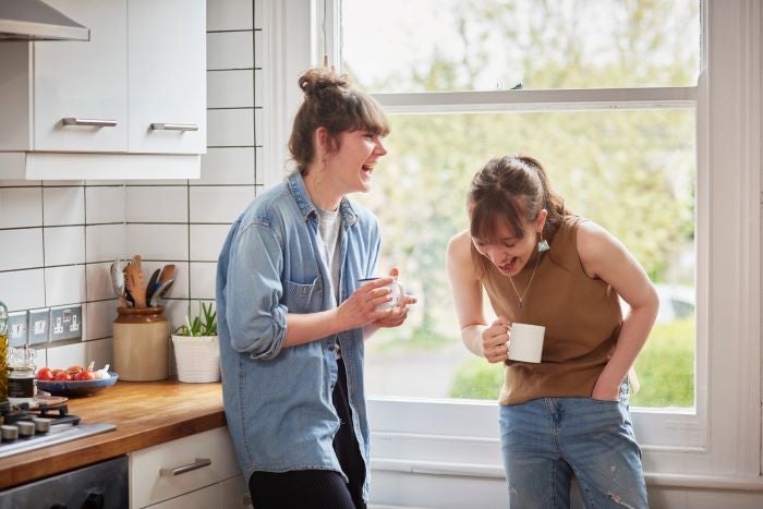 2 young woman laughing in a kitchen 