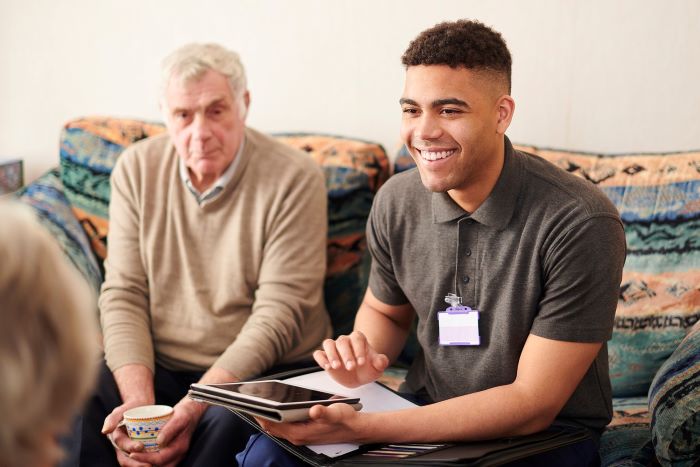 housing support worker talking to two resident in their living room