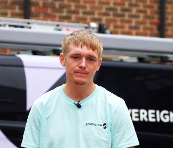 A Sovereign Plumber standing in front of his work van and smiling at the camera