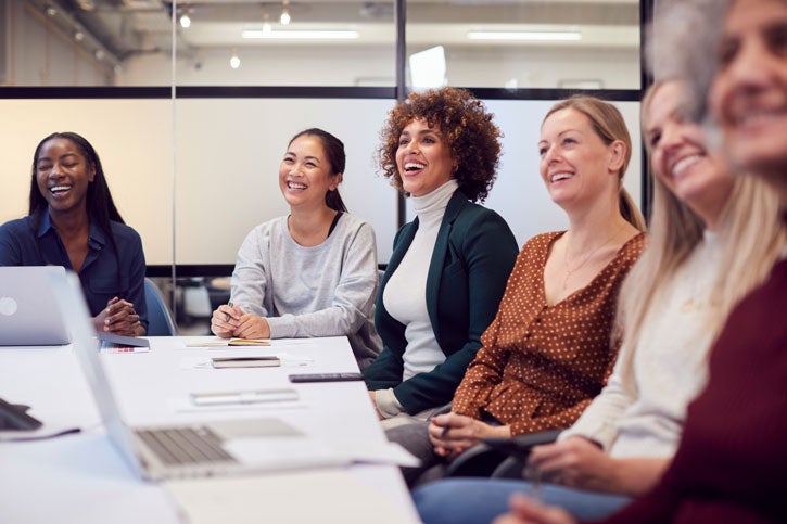 A group of women sitting around a table in a boardroom