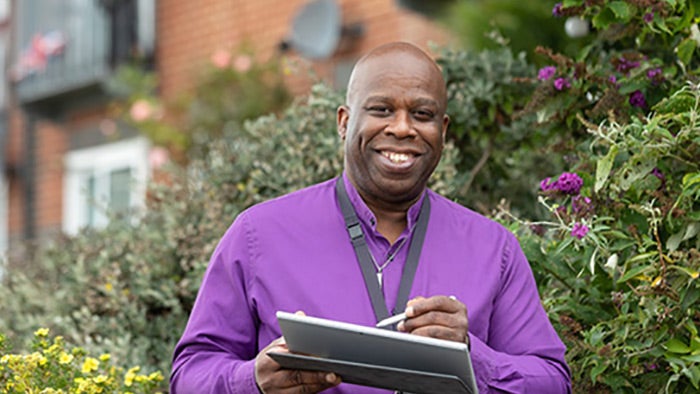 Sovereign employee holding an iPad and smiling at the camera.