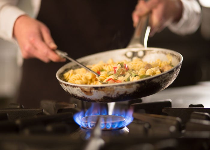 A close up of a pan of food being cooked over a gas flame